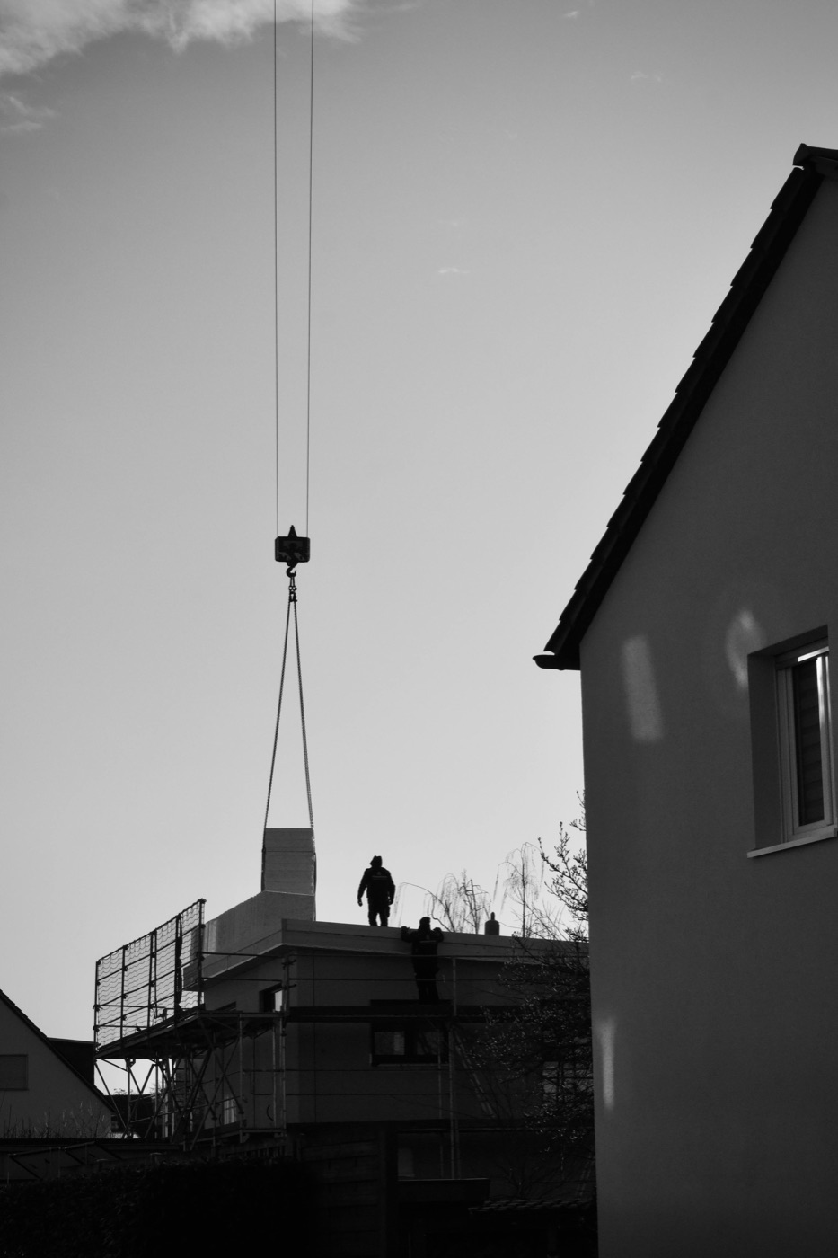 Kran am Rohbau in der Abendsonne — Dachdecker bei der Arbeit