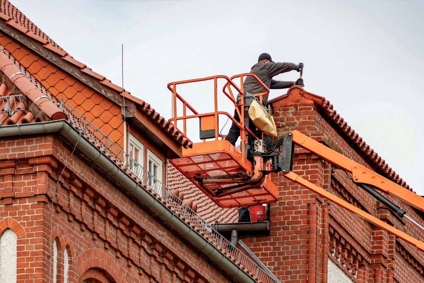 Dachdecker auf Hubbühne an Backsteinaltbau